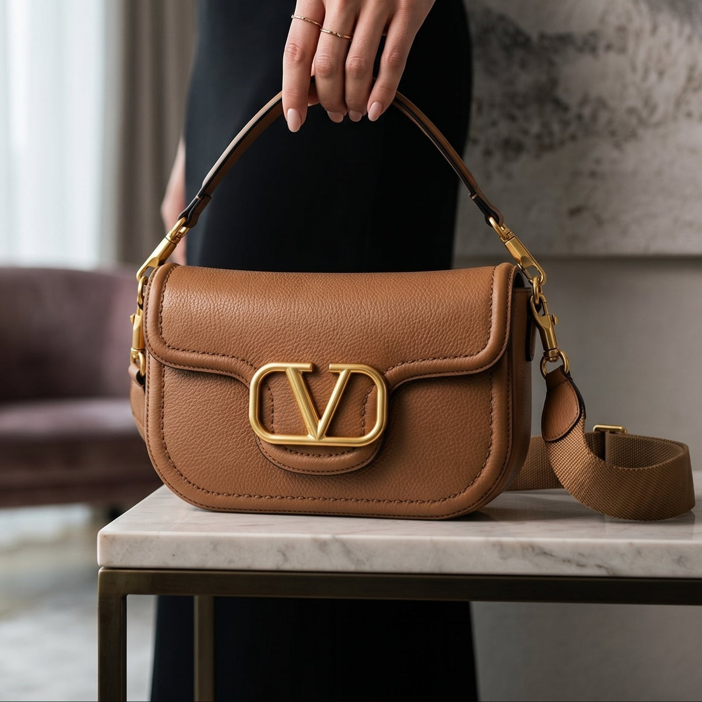 Model holding Valentino Alltime Leather Shoulder Bag in modern interior on marble table. 